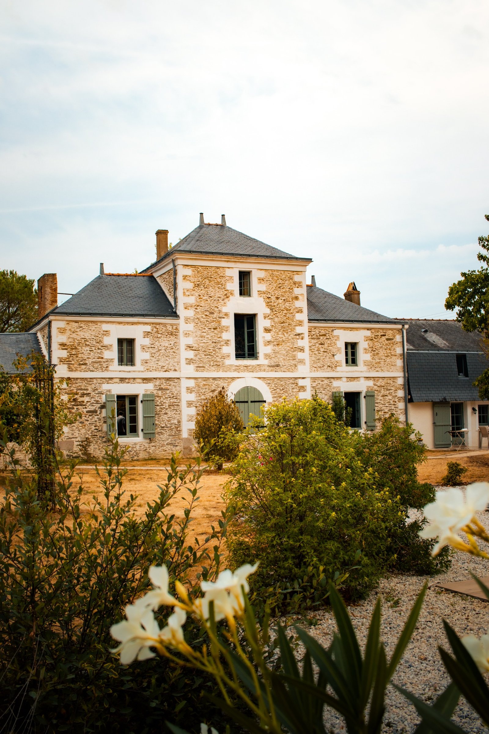 Historic French stone estate surrounded by gardens, with white flowers in the foreground