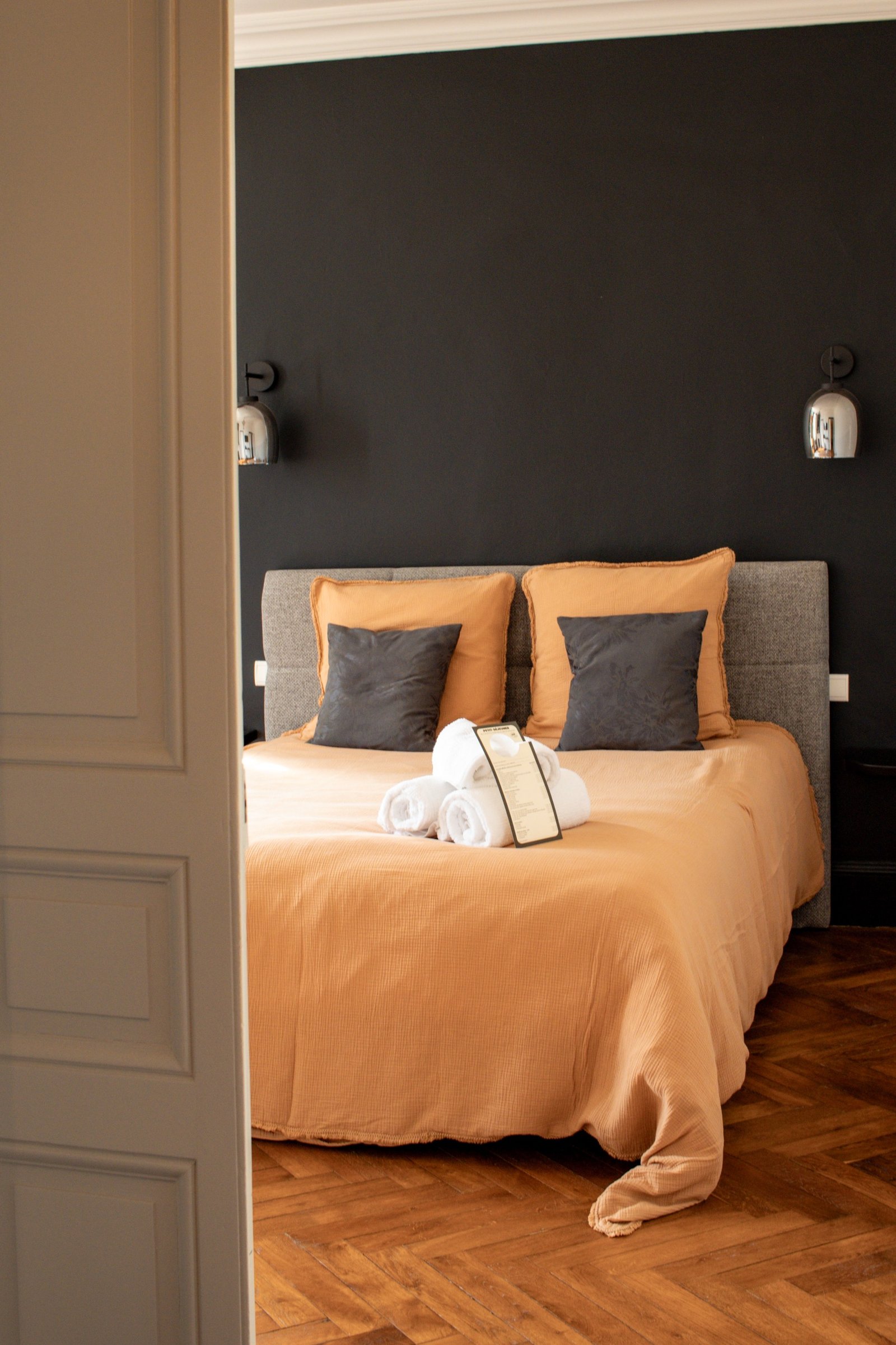 Warmly lit bedroom with terracotta linen viewed through an open doorway