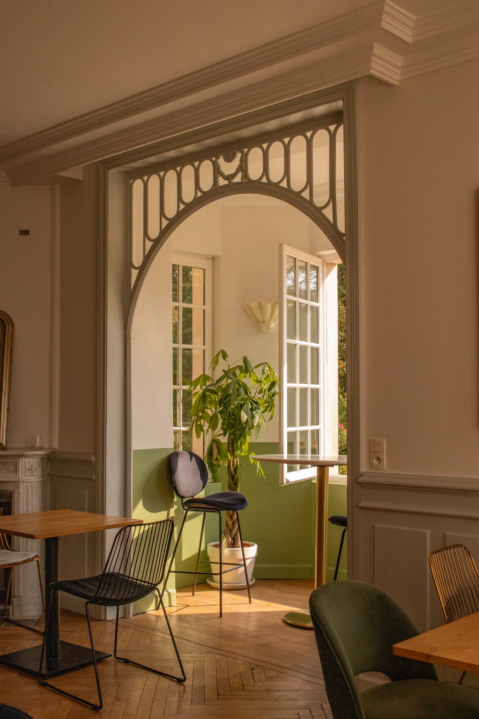 Decorative historic arch framing an open window and soft green walls